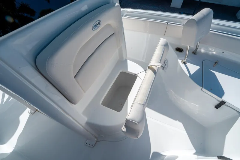 Slide: The Image of 2025 Sea Hunt Ultra 235 SE boat interior, featuring white cushioned seating and storage compartment. - 24