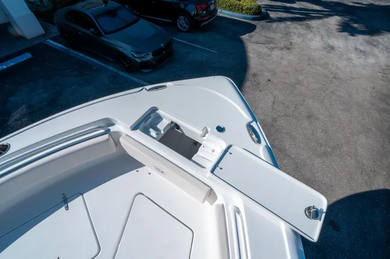 Slide: The Image of Sea Hunt Ultra 235 SE 2025 boat bow with open storage compartment, parked cars nearby. - 26