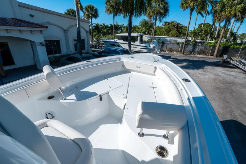 Slide: The Image of 2025 Sea Hunt Ultra 235 SE boat, spacious deck, white interior, palm trees in background. - 22