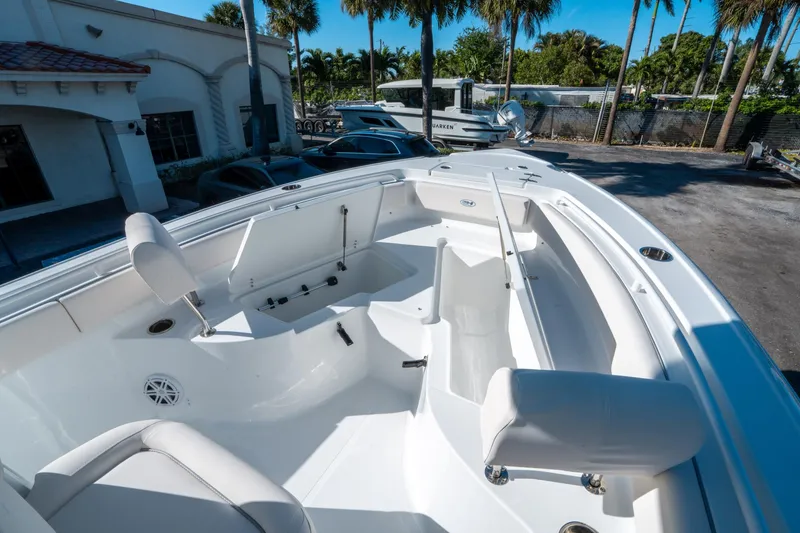 Slide: The Image of 2025 Sea Hunt Ultra 235 SE boat interior with seating and storage, parked outdoors. - 23