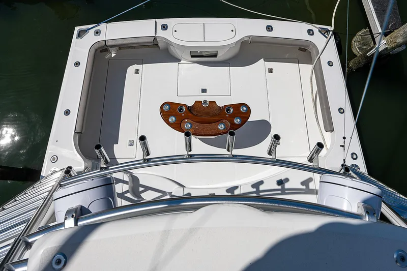 Slide: The Image of 2012 Cabo 44 HTX boat deck with fishing rod holders and wooden detail. - 35
