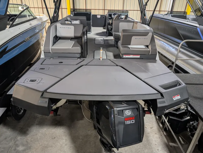 Slide: The Image of 2025 Manitou Cruise boat with modern seating and powerful engine in a showroom. - 1