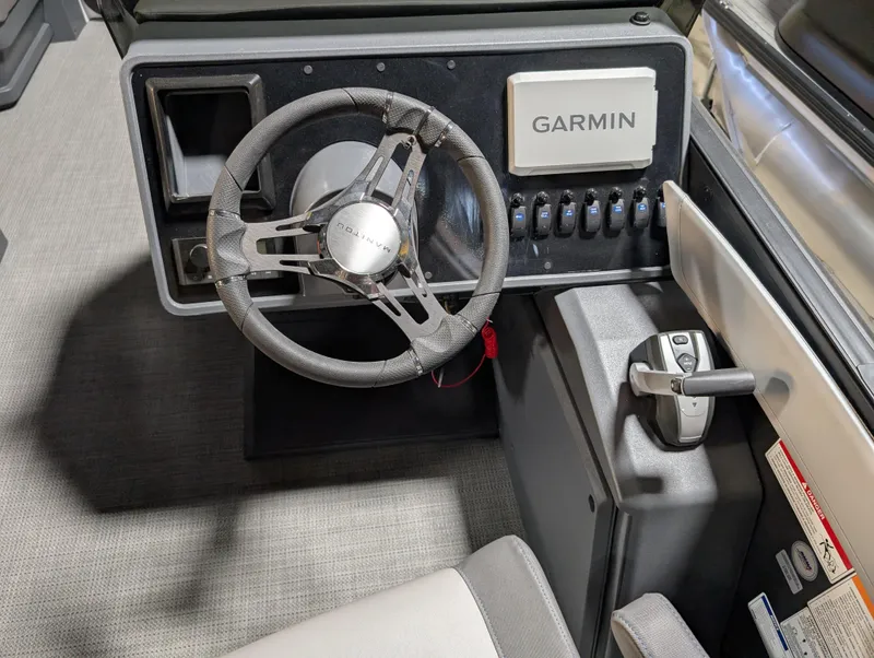 Slide: The Image of 2025 Manitou Cruise boat dashboard with Garmin navigation system and steering wheel. - 10
