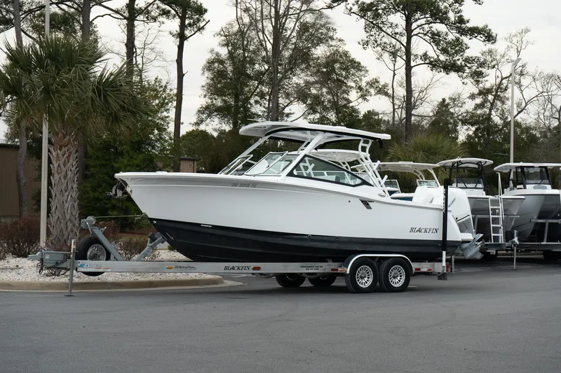 The Image of 2023 Blackfin 272 DC boat on trailer, parked outdoors with trees in background. - 1
