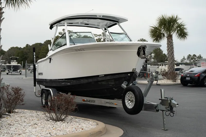Slide: The Image of 2023 Blackfin 272 DC boat on trailer in a parking lot with palm trees. - 4