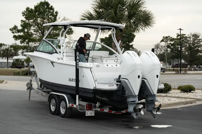 Slide: The Image of 2023 Blackfin 272 DC boat on trailer with dual engines in a parking lot. - 6