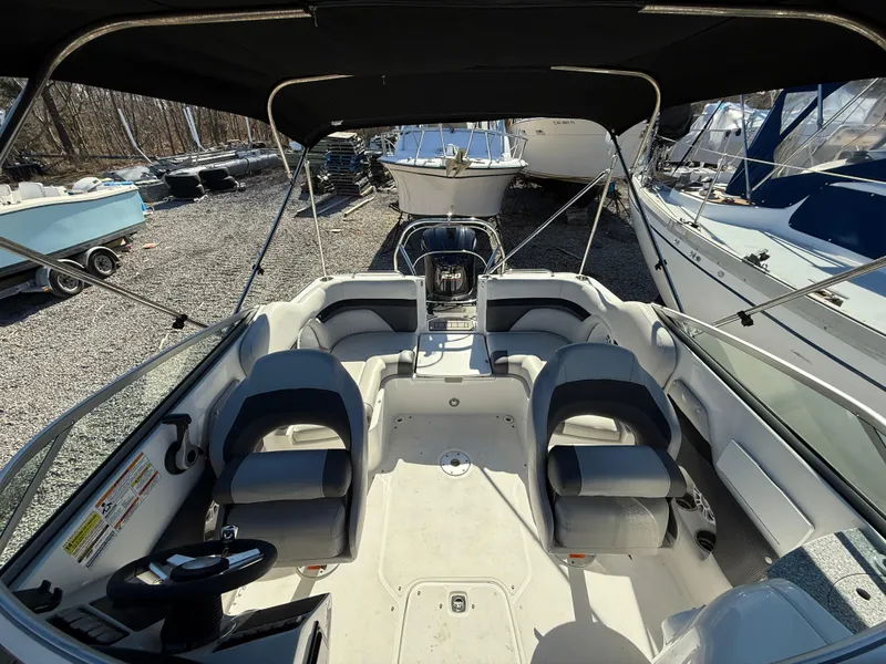 Slide: The Image of 2018 Hurricane SunDeck 2486 OB boat interior with seating and steering wheel, docked outdoors. - 13