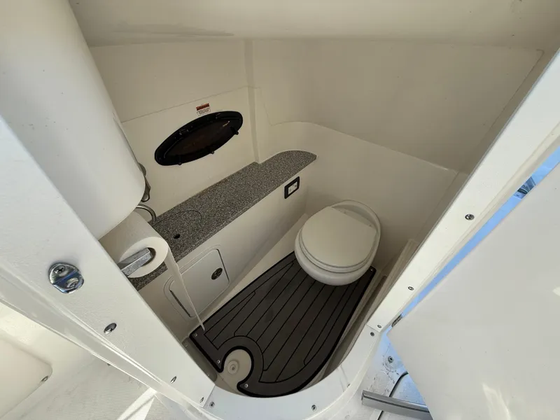 Slide: The Image of 2018 Hurricane SunDeck 2486 OB boat interior with compact bathroom and toilet. - 14