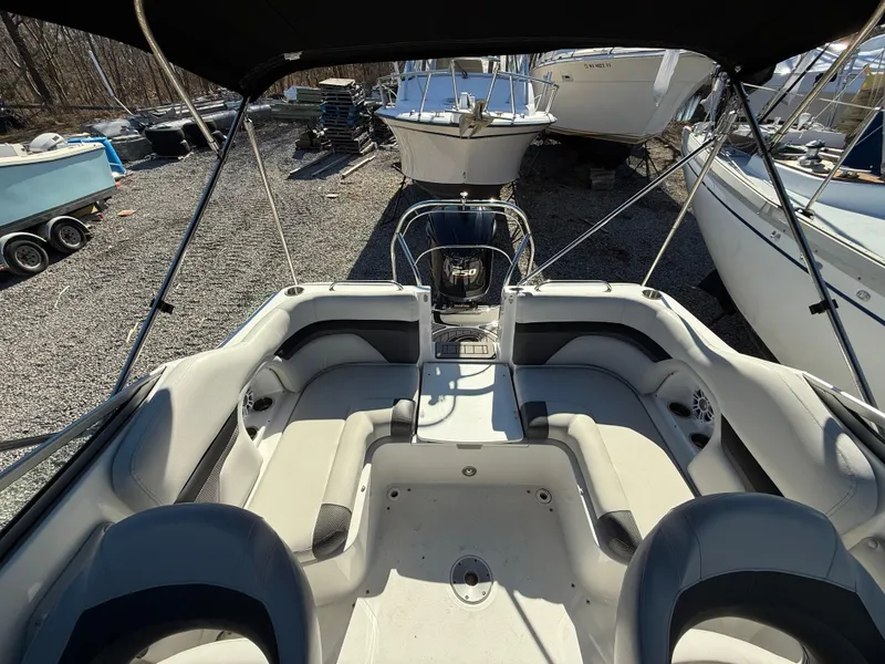 Slide: The Image of 2018 Hurricane SunDeck 2486 OB boat interior with seating, parked among other boats. - 18