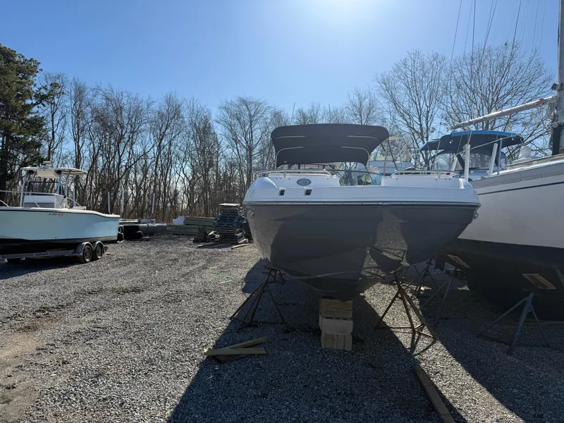 Slide: The Image of 2018 Hurricane SunDeck 2486 OB boat on gravel lot, surrounded by trees and other boats. - 20