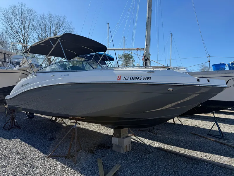 Slide: The Image of 2018 Hurricane SunDeck 2486 OB boat on stands, with a black canopy, in a marina. - 21