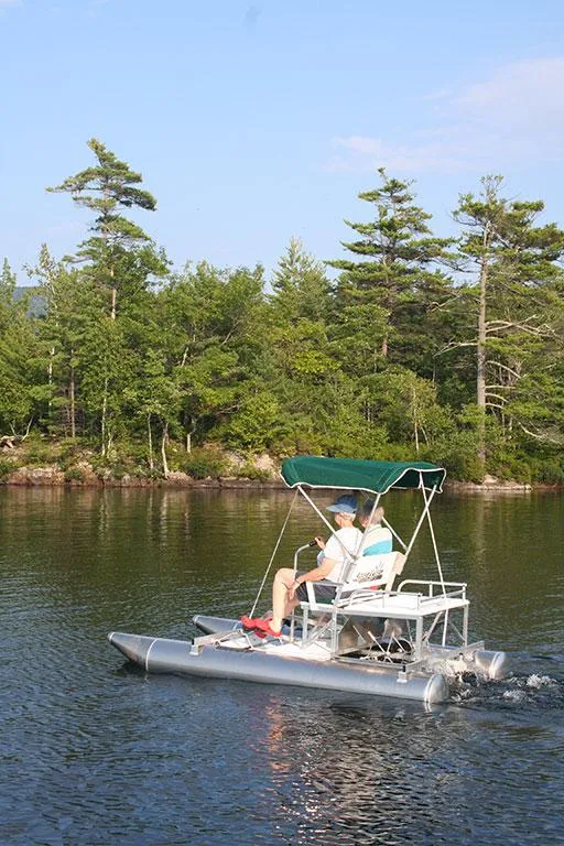 Slide: The Image of 2024 Aqua Cycle AC15W pontoon boat on a serene lake with lush green trees. - 1