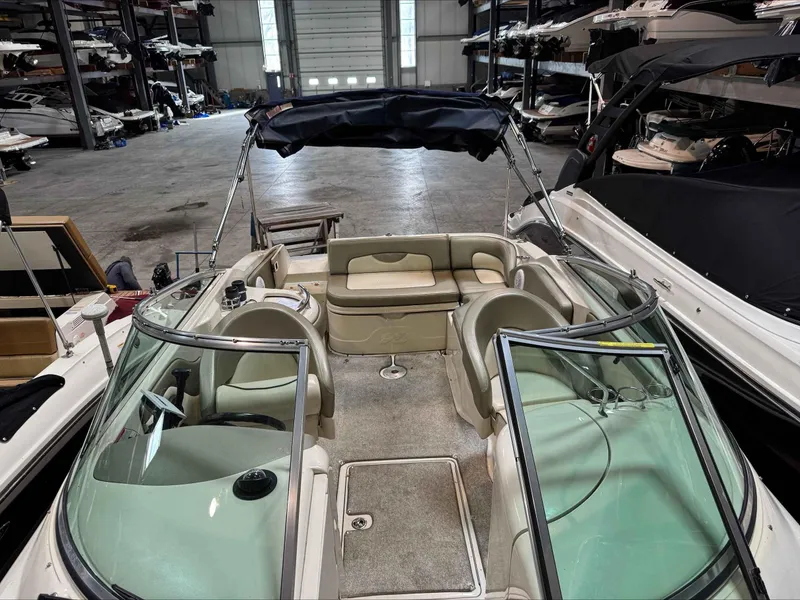 Slide: The Image of 2005 Sea Ray 270 Sundeck boat interior in storage facility, featuring seating and windshield. - 7