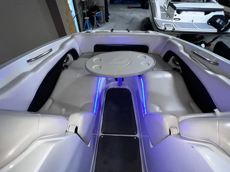 Slide: The Image of 2013 Crownline Eclipse E4 boat interior with seating and table, featuring blue LED lighting. - 13