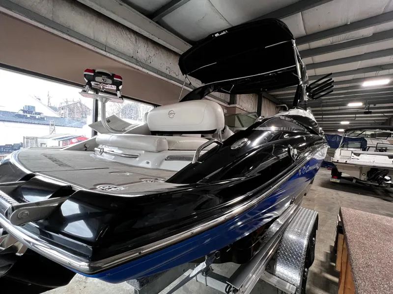 Slide: The Image of 2013 Crownline Eclipse E4 boat in a showroom, featuring sleek black and blue design. - 4