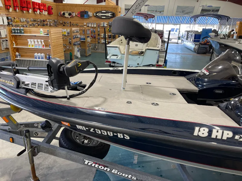Slide: The Image of 2009 Triton 18 HP Explorer boat displayed in a showroom with accessories. - 10
