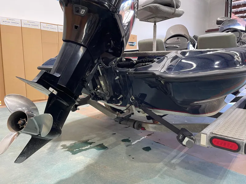 Slide: The Image of 2009 Triton 18 HP Explorer boat on trailer, showing motor and propeller in a garage. - 15