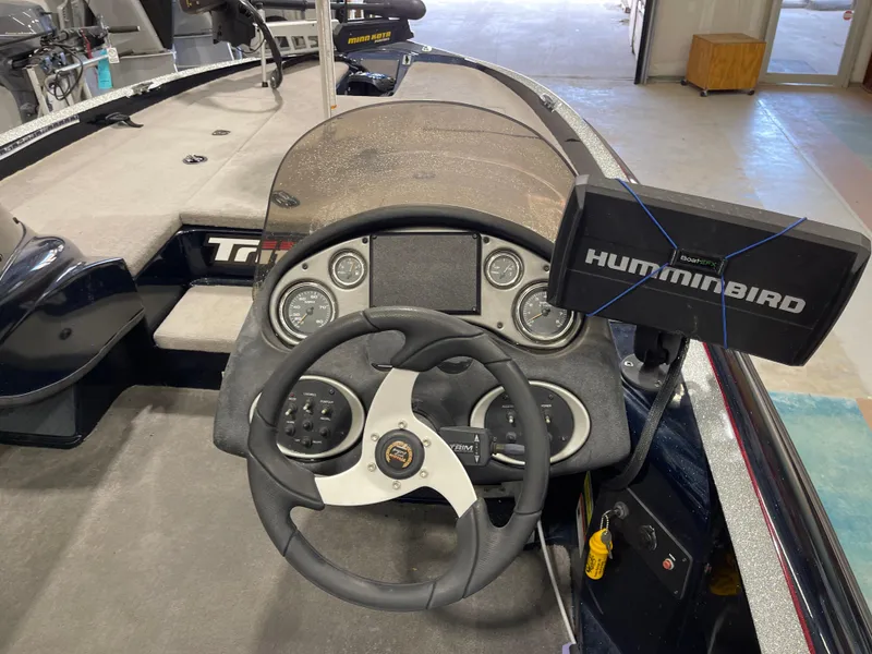 Slide: The Image of 2009 Triton 18 HP Explorer boat dashboard with steering wheel and Humminbird fish finder. - 18