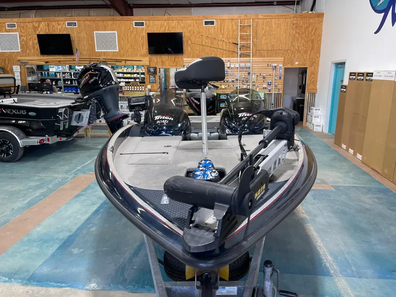 Slide: The Image of 2009 Triton 18 HP Explorer boat displayed in a showroom with fishing equipment. - 7