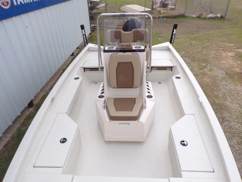 Slide: The Image of 2025 Xpress H20BAY boat interior with seating and console, parked outdoors. - 15