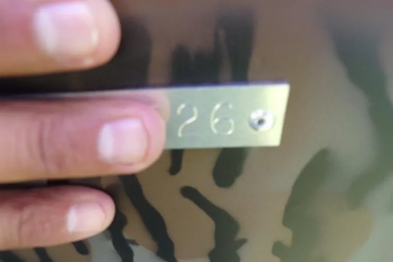 Slide: The Image of Close-up of a hand touching a metal plate with the number "26" on Xpress XP200, 2026. - 8