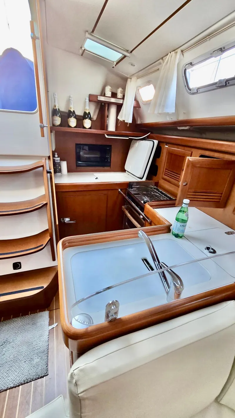 Slide: The Image of 2006 Beneteau 393 yacht interior with kitchen, wooden cabinetry, and modern appliances. - 18