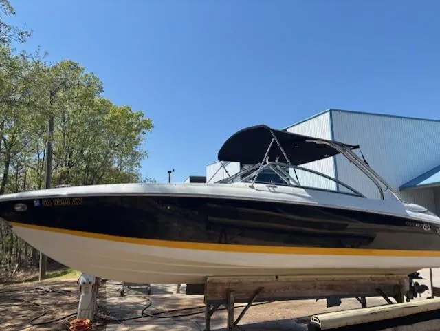 Slide: The Image of 2005 Cobalt 272 boat with black hull and canopy, displayed outdoors near a building. - 1