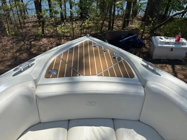 Slide: The Image of Bow of 2005 Cobalt 272 boat with white seating and wooden deck, surrounded by trees. - 11