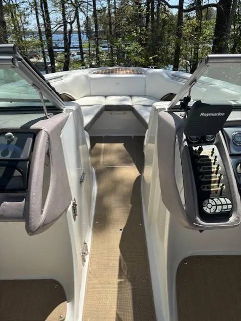 Slide: The Image of 2005 Cobalt 272 boat interior with seating and control panel, surrounded by trees. - 26