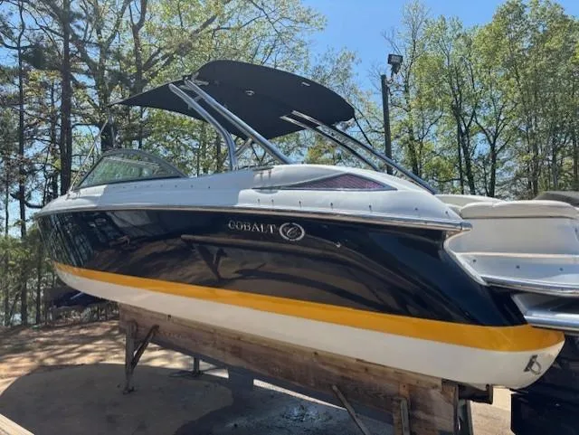 Slide: The Image of 2005 Cobalt 272 boat with black and yellow hull, docked outdoors. - 3
