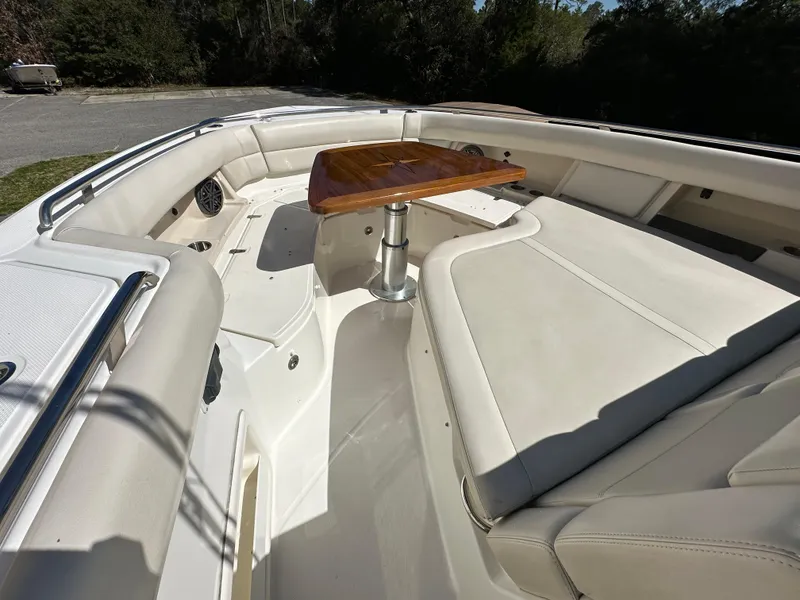 Slide: The Image of 2021 Boston Whaler Realm 380 boat interior with cushioned seating and wooden table. - 18
