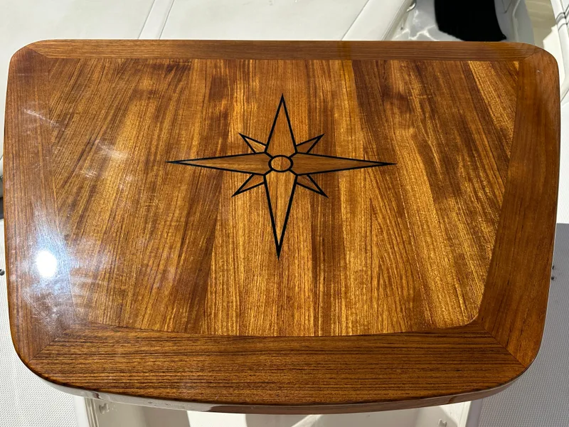 Slide: The Image of Wooden table with compass rose design on a 2021 Boston Whaler Realm 380 boat. - 19