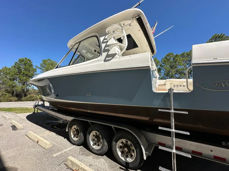 Slide: The Image of 2021 Boston Whaler Realm 380 boat on a trailer, parked outdoors under clear blue sky. - 3
