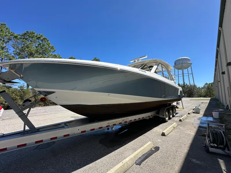 Slide: The Image of 2021 Boston Whaler Realm 380 boat on trailer, parked outdoors under clear blue sky. - 6
