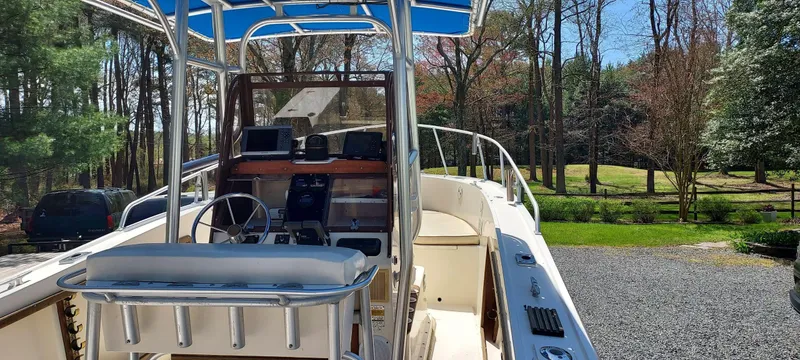 Slide: The Image of 1990 Mako 261 Center Console boat with blue canopy, parked outdoors. - 13