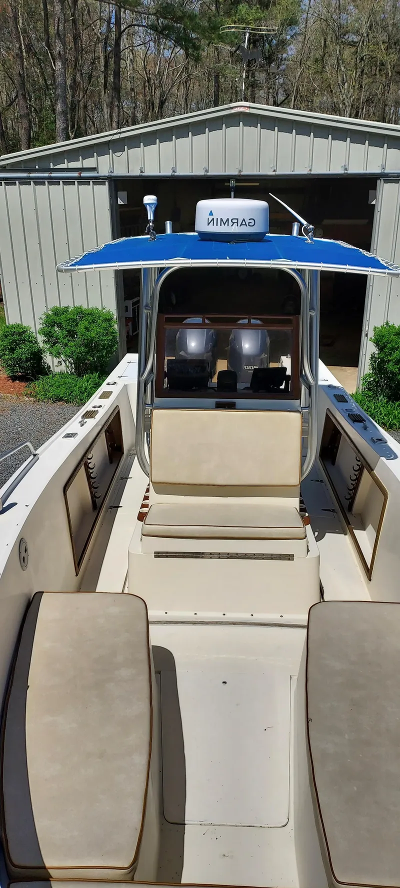 Slide: The Image of 1990 Mako 261 Center Console boat with seating, parked near a shed. - 14