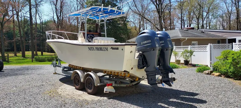 Slide: The Image of 1990 Mako 261 Center Console boat with dual engines on a trailer. - 2