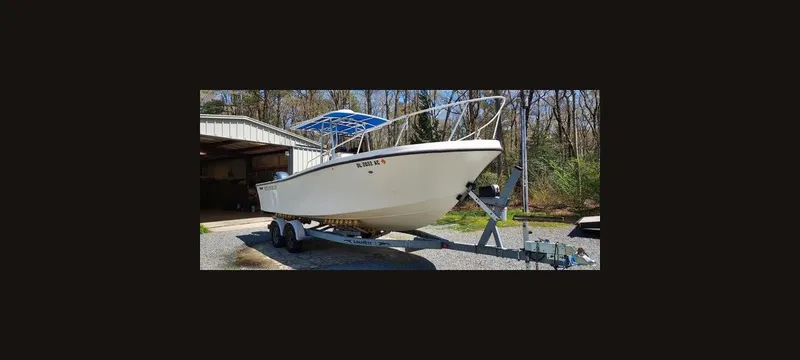Slide: The Image of 1990 Mako 261 Center Console boat on trailer, parked outdoors near a garage. - 20