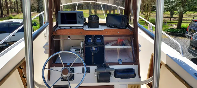 Slide: The Image of 1990 Mako 261 Center Console boat dashboard with steering wheel and navigation equipment. - 6