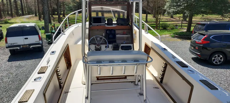 Slide: The Image of 1990 Mako 261 Center Console boat with spacious deck and steering console, parked outdoors. - 7
