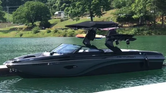 Slide: The Image of 2019 Centurion Ri237 boat on a serene lake with lush green surroundings. - 8