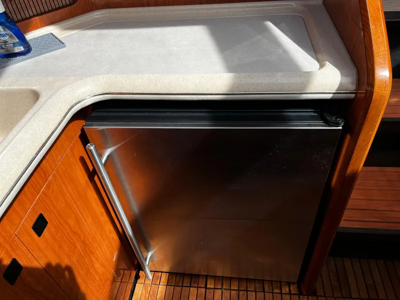 Slide: The Image of 2001 Sea Ray 420 Aft Cabin kitchen with stainless steel fridge and wooden cabinetry. - 36