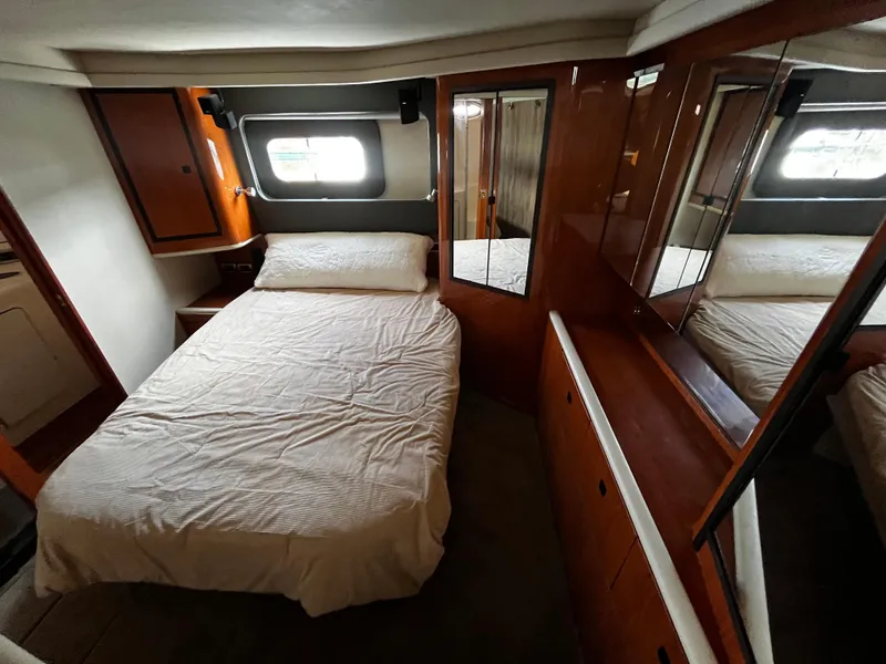Slide: The Image of 2001 Sea Ray 420 Aft Cabin bedroom with bed, wooden cabinets, and window. - 45