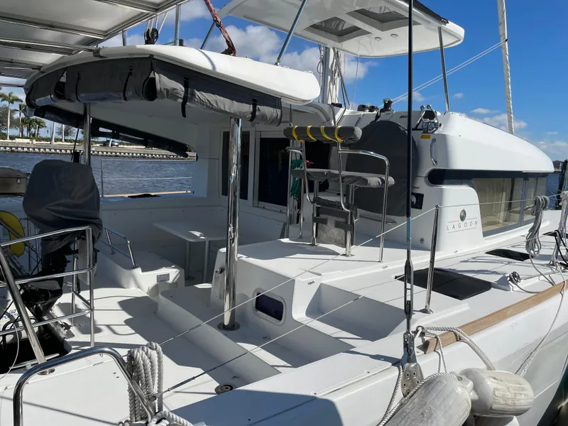 Slide: The Image of 2017 Lagoon 39 catamaran with spacious deck, docked by the water under a clear blue sky. - 4