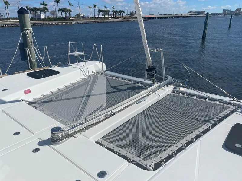 Slide: The Image of 2017 Lagoon 39 catamaran with netted deck, docked by calm waters and palm trees. - 8