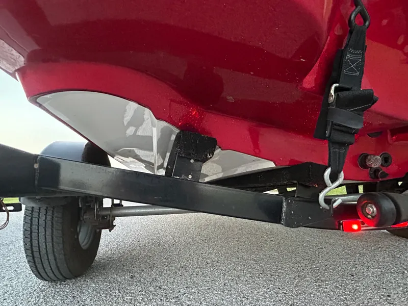 Slide: The Image of Red Nitro Z7 boat trailer, 2015 model, showing undercarriage and wheel on asphalt. - 32