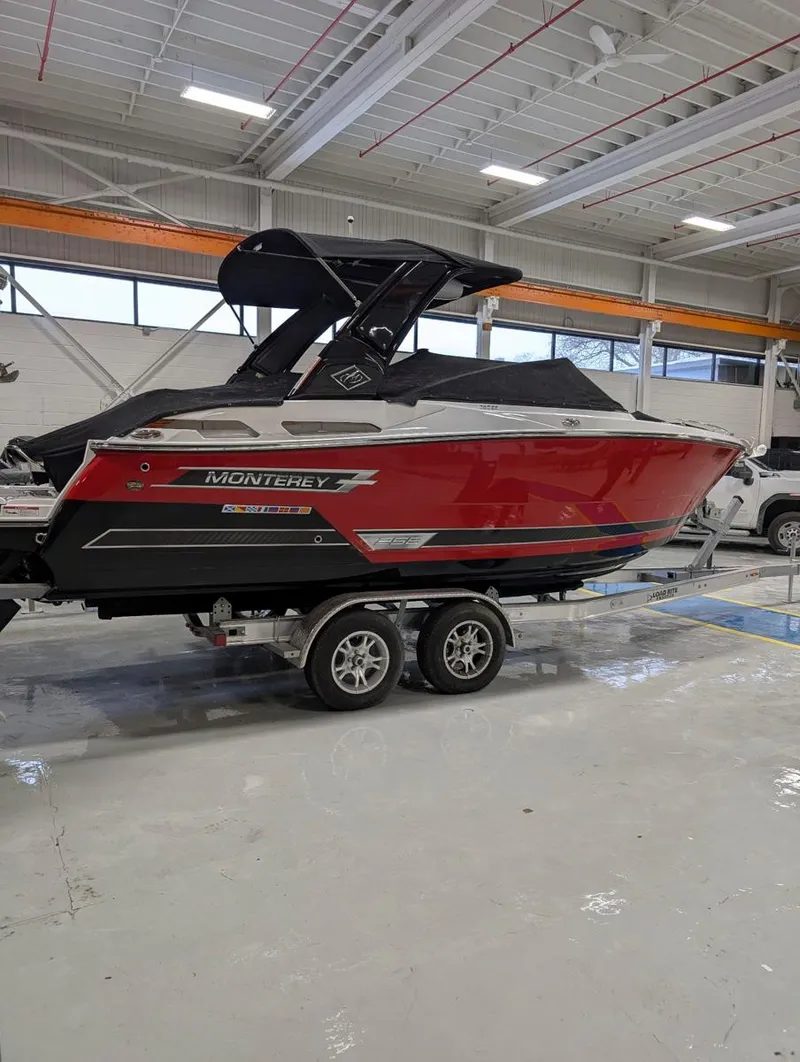 Slide: The Image of 2022 Monterey 258 Super Sport boat in showroom, red and black design, on a trailer. - 28