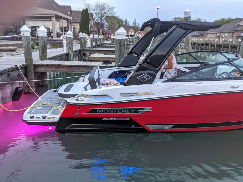 Slide: The Image of 2022 Monterey 258 Super Sport boat docked, featuring vibrant red exterior and illuminated underwater lights. - 4