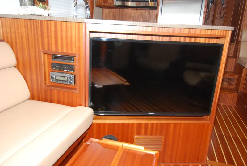 Slide: The Image of 2015 American Tug 485 interior with TV, wood paneling, and beige seating. - 24
