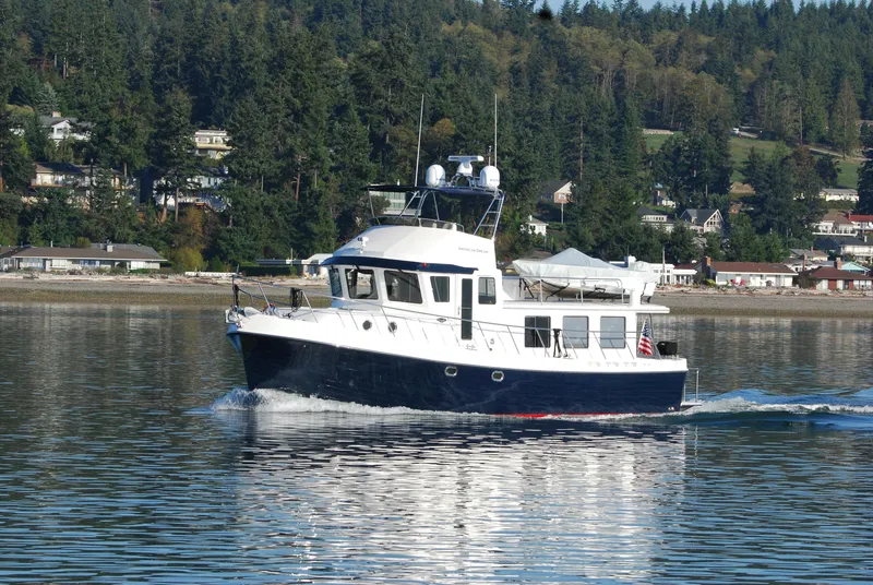 Slide: The Image of 2015 American Tug 485 cruising on a calm lake with forested shoreline. - 3
